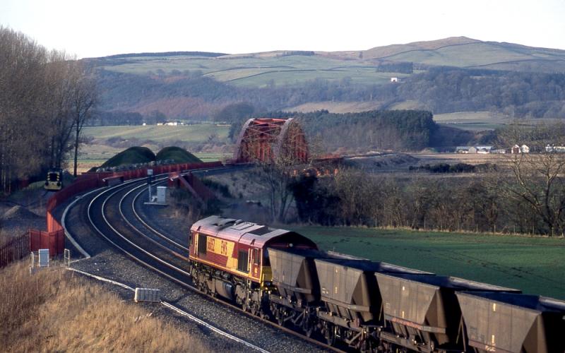 Portrack: 66052 heads north up the G&SW with an empty MGR. On the left is the privately owned Ruston Hornsby shunter D2957. The new bridge over the River Nith is in the background. 10 February 2006 Photo of Portrack