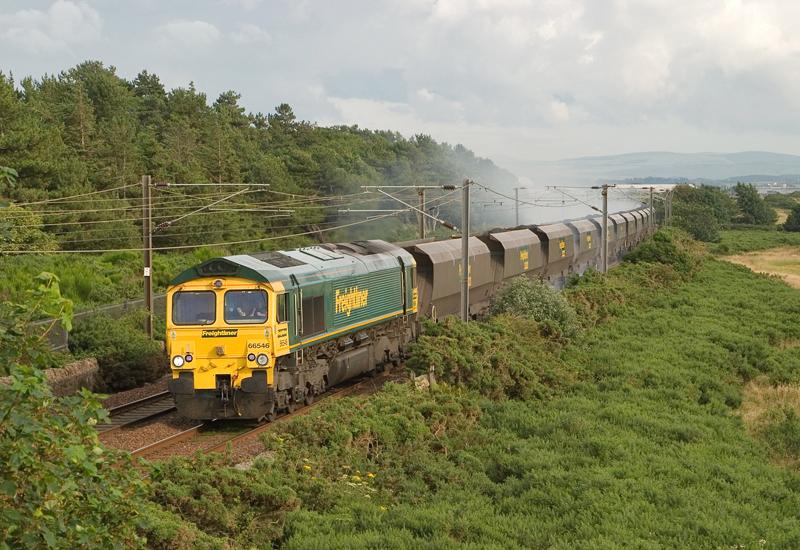 66546 in a bit of bother at Lochgreen: 66546's train appears to have binding brakes as it passes the former site of Lochgreen Jn between Prestwick Airport and Troon on 6M27 ex-Killoch. 2009 Photo of 66546 in a bit of bother at Lochgreen