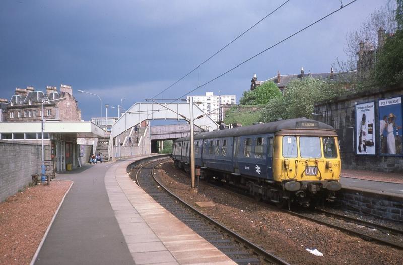303083 at Hamilton Central: 303083 on a Glasgow - Bellshill - Hamilton - Glasgow service on 23 May 1978. The station building, now demolished, was a standard design widely used in the Strathclyde area. Photo of 303083 at Hamilton Central