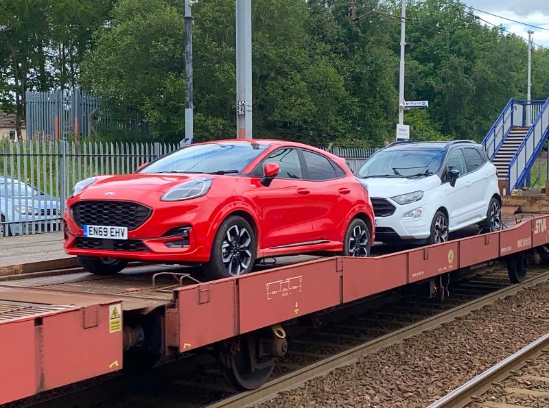 Fords On Board : On August 20, 2020, a pair of brand new Fords are seen tagging along on what would normally be an empty load on 6L35 Mossend - Dagenham Dock, which was lead by DB Red shed 66135. Photo of Fords On Board