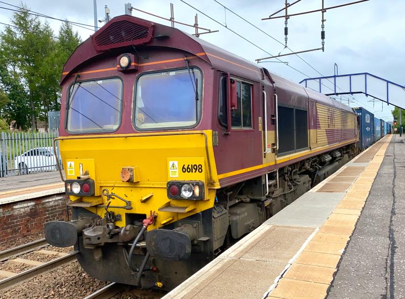 Class 8 Crawl: A very rare instance of a Class 8 headcode working in Scotland. EWS branded DB Class 66, 66198 slowly rumbles through Holytown working 8Z25 from Carstairs to Mossend, with some defective container wagons from 4M25 in tow. Photo of Class 8 Crawl