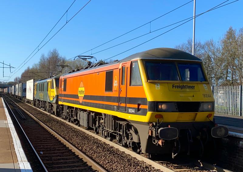 Early Orange: Seemingly running in an earlier path, 90044 leads the 4L89 16:32 from Coatbridge FLT to Felixstowe through Holytown with Powerhaul 90043 in tow beneath a cloudless sky. (01/04/2021) Photo of Early Orange