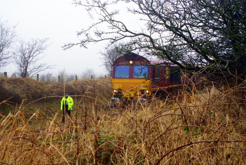 66 067: A police officer stands gaurd as 66 067 sits and waits as the clean up goes on, after a bridge gave way and it lost a few of its wagons, near stewarton. (photo, Greig Gibson) Photo of 66 067