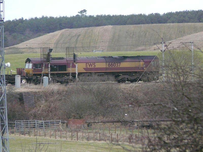 66037 on 6E28: DBS 66037 climbs to Cobbinshaw with the 6E28 Dalzell to Tees Yard steel empties on 5-2-11. Photo taken from Carstairs South Jn roadbridge on long telephoto shot. Photo of 66037 on 6E28