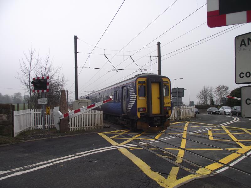 156 495 Depart Kirknewton 16/03/2011: 156 495 in Saltire Livery departs from Kirknewton station on 16/03/2011, note the barriers rising before the train has fully passed over the crossing. Photo of 156 495 Depart Kirknewton 16/03/2011